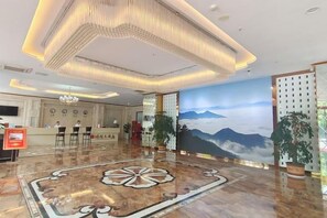 Un vestíbulo de hotel con mostrador de recepción, zona de estar y un gran mural de montañas.