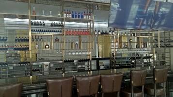 A bar area with multiple shelves of bottles and glasses, and several brown chairs.