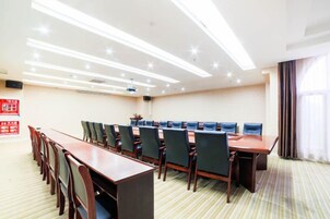 A conference room with a long table and chairs, a projector, and a large window with curtains.