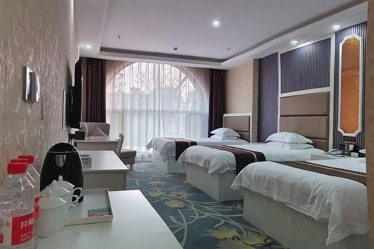 Habitació d'hotel amb dos llits, una escriptori, una cadira, una taula petita, un mirall i una finestra amb cortines.
