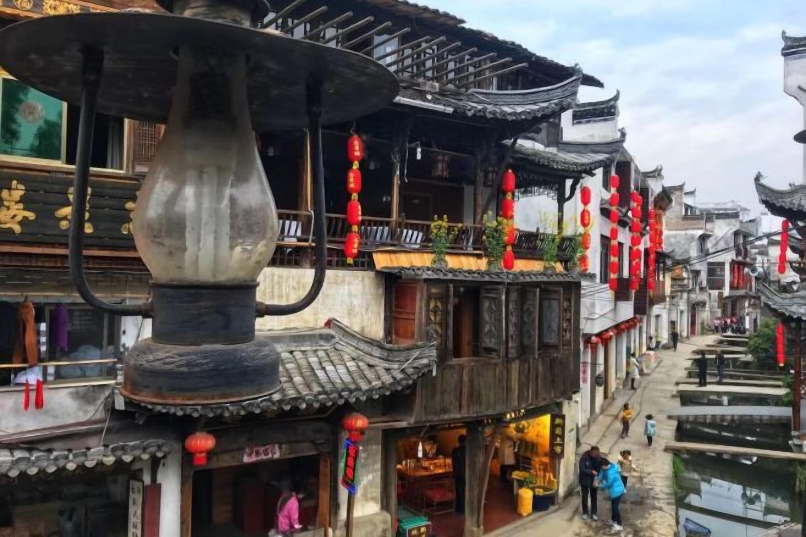 Un edificio tradicional con una fuente en primer plano, balcones de madera y faroles rojos.