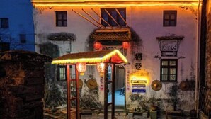 Il s’agit d’un bâtiment traditionnel, doté d’une structure à toit de chaume à l’avant, qui pourrait être une maison de thé ou un site culturel.