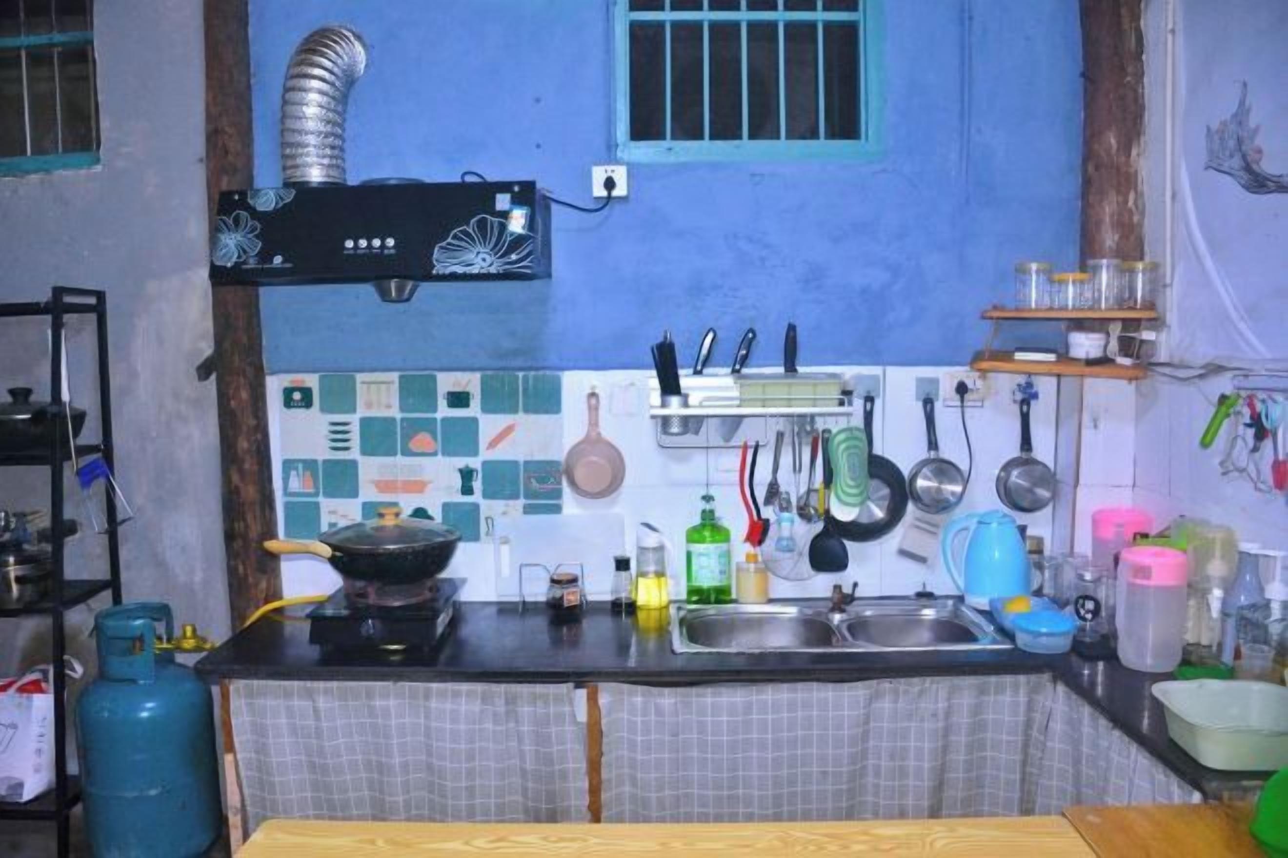 Una cocina con estufa a gas, pileta y diversos utensilios.