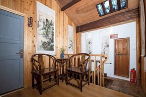 A wooden interior with a blue door, wooden chairs, a small table, and a staircase leading to another room. - Alley Time Inn (Wuyuan)