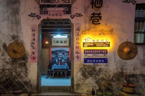 A traditional Chinese gate with a signboard, a table with chairs, and a potted plant. - Alley Time Inn (Wuyuan)