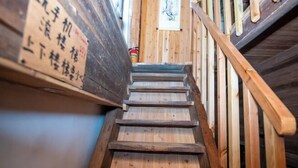 Un escalier en bois muni d’une rampe et d’une enseigne avec des caractères japonais.