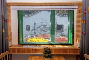 A window with a view of a bridge and a buffet table with various food items. - Alley Time Inn (Wuyuan)