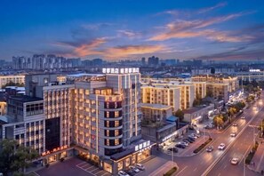 A multi-story hotel with a modern design, featuring a prominent entrance and a parking area. - Wenjukejun Hotel (Bubugao Plaza Xiangtan Iron and Steel Co., Ltd. Branch) (Xiangtan)