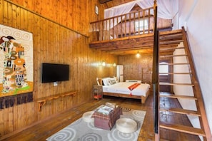 Un interior de madera con una cama, un televisor, una escalera y una pared con un mural colorido.
