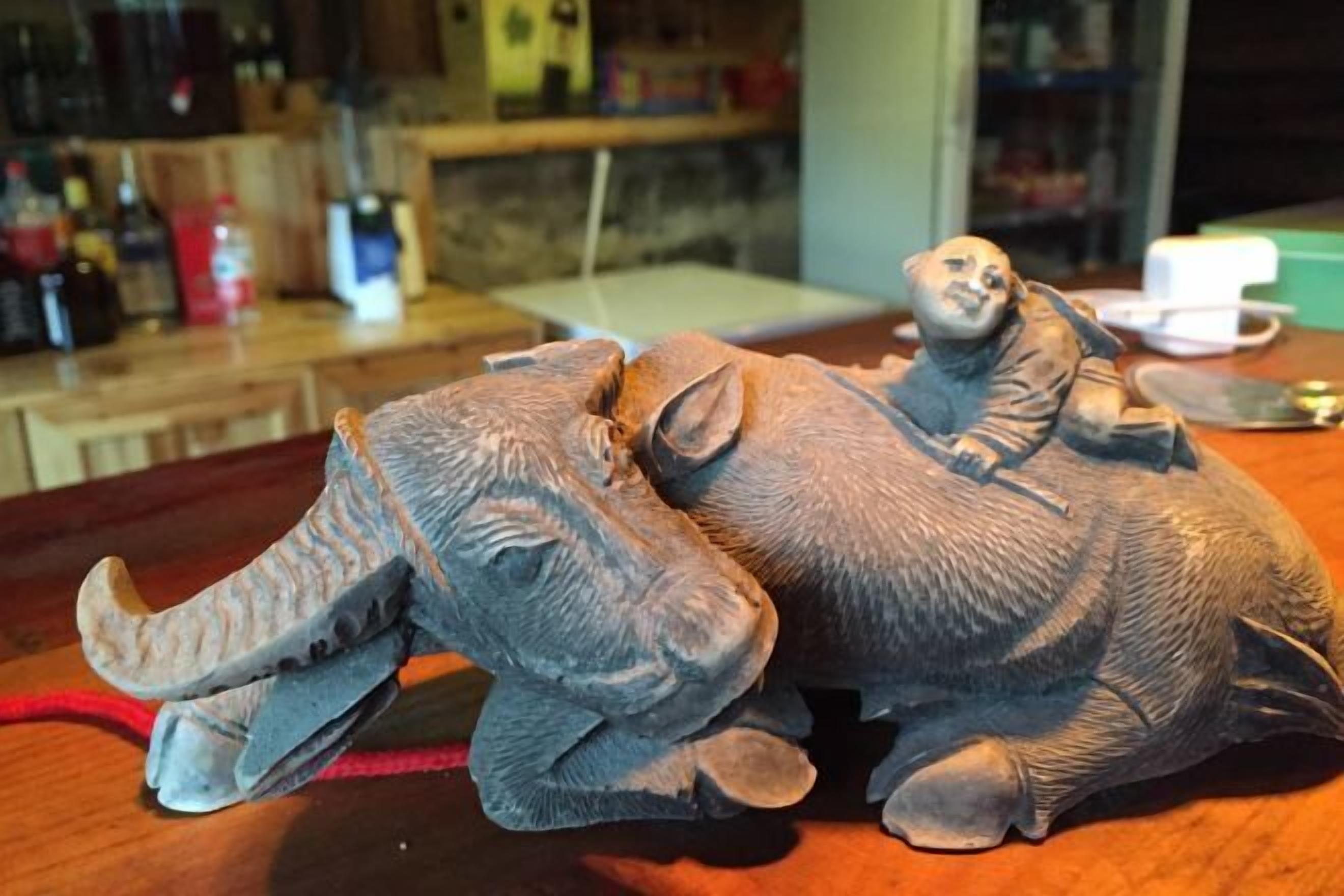 A sculpture of an elephant and a rider on a wooden table.