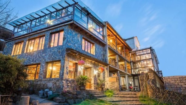 Ein modernes Haus mit Steinverkleidung, großen Fenstern und einem Glasbalkon.
