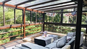 Ein moderner Außenbereich mit Lounge-Möbeln, einer Glasveranda und einem Holzboden.