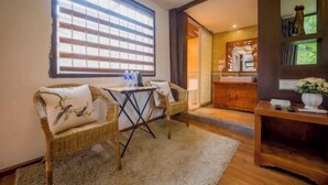 A room with a large window, wicker chairs, a small table, a wooden cabinet, and a mirror. - Sisigu View Inn (Lijiang)
