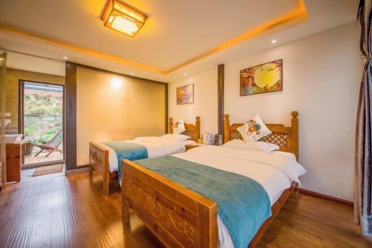 A hotel room with two wooden beds, a large window, and a door leading to a balcony.