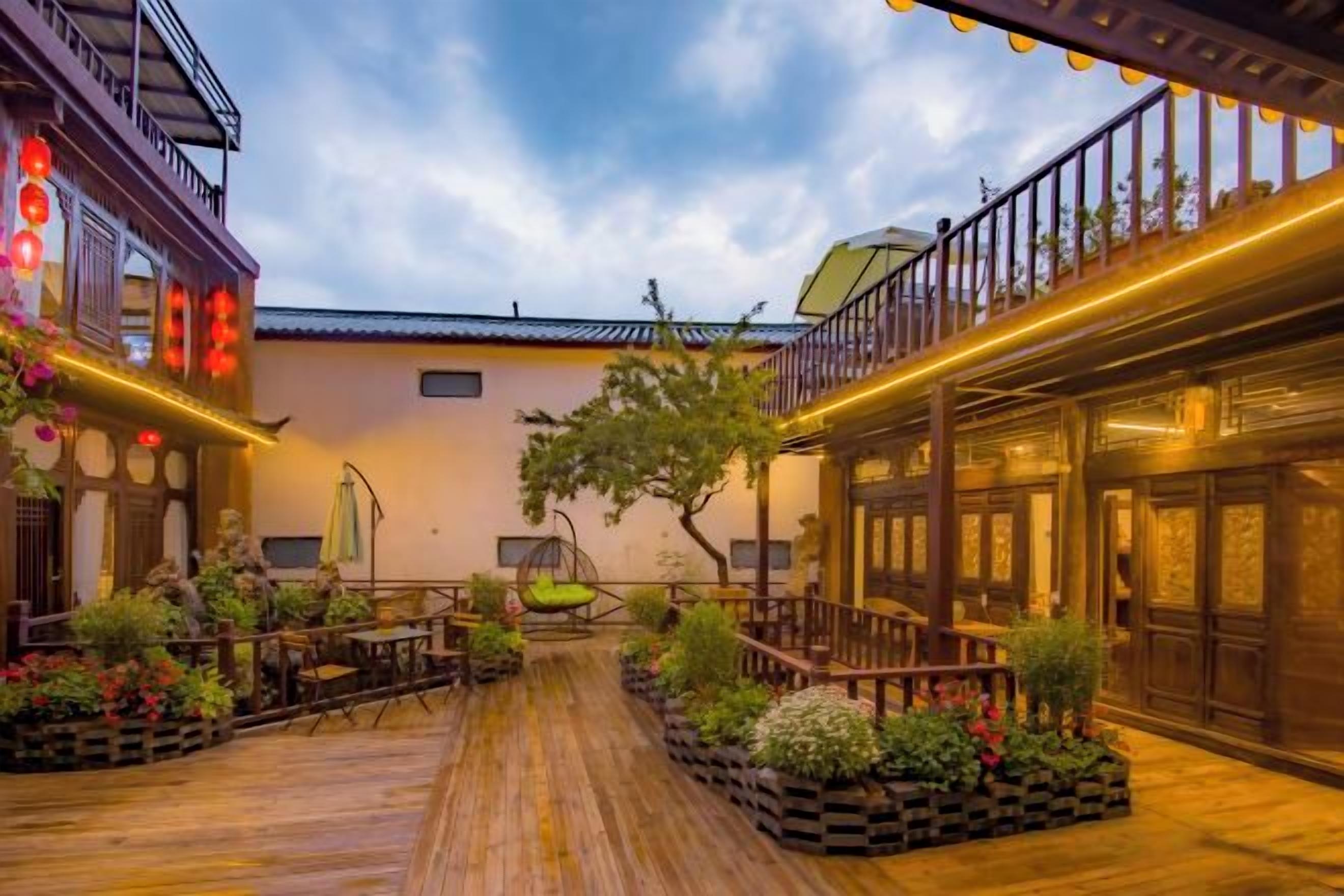 A courtyard with wooden flooring, potted plants, and a hanging chair.