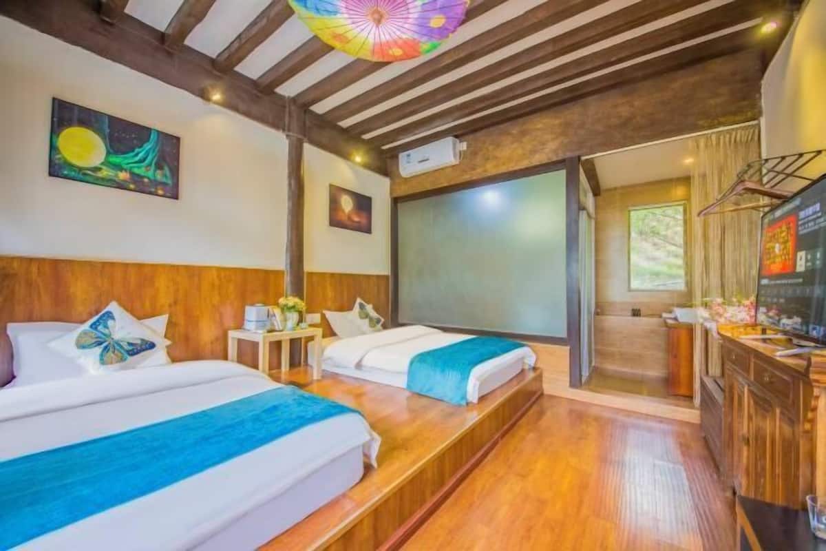 A hotel room with two beds, a wooden ceiling, a TV, and a desk with a chair.