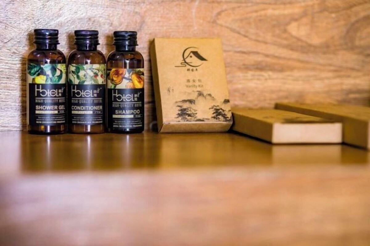 Três frascos de gel de banho, condicionador e champô de hotel, e uma caixa de sabonete.