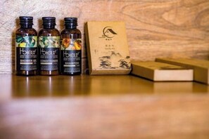 Três frascos de gel de banho, condicionador e champô de hotel, e uma caixa de sabonete.