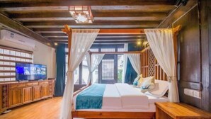 A bedroom with a wooden bed, white curtains, a television, and a wooden cabinet. - Sisigu View Inn (Lijiang)