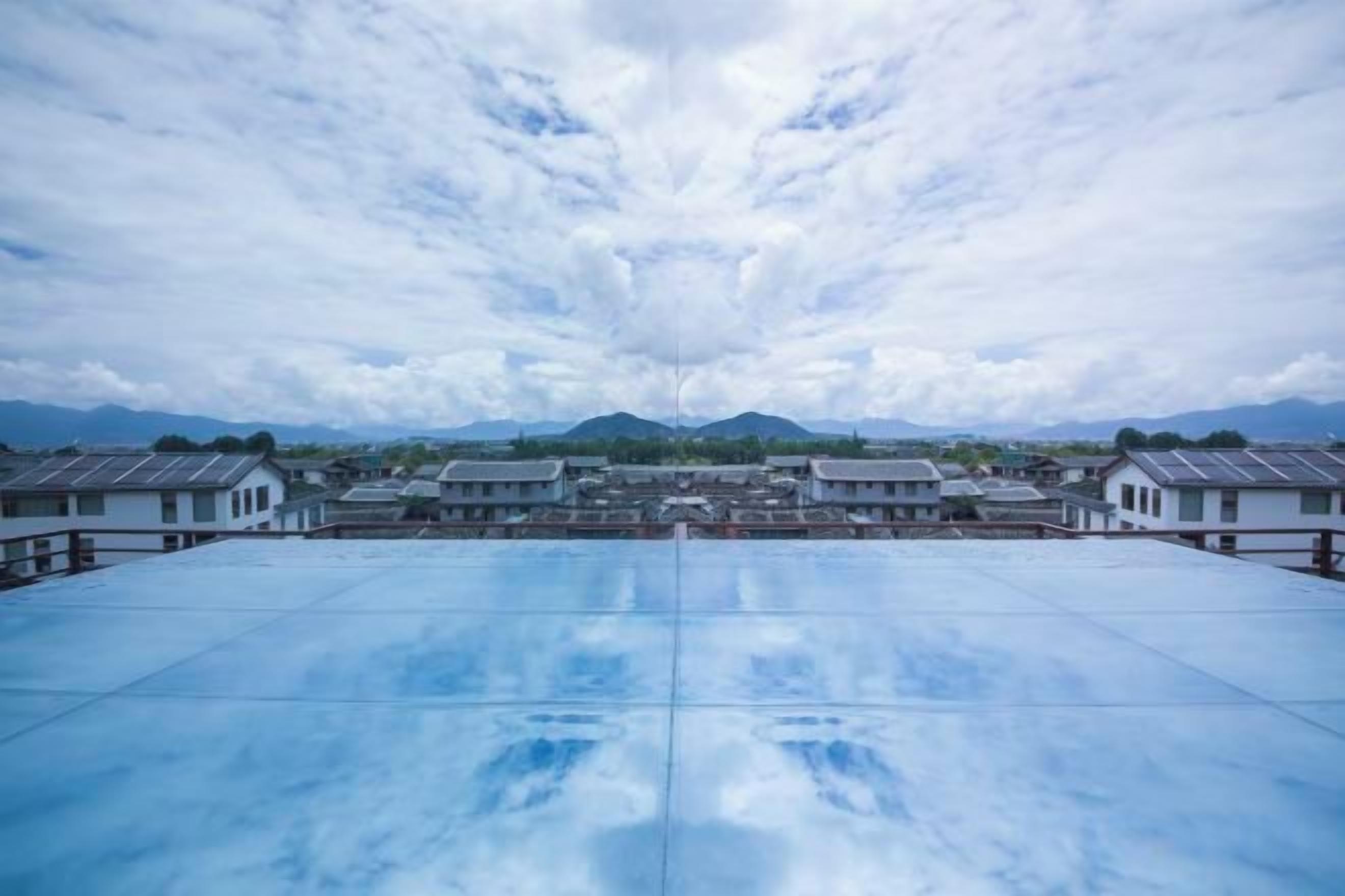 A rooftop with a clear view of a traditional building complex and distant mountains.