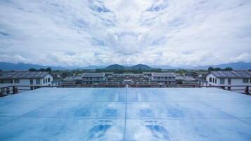 A rooftop with a clear view of a traditional building complex and distant mountains.
