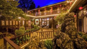 A traditional-style building with a courtyard, wooden railings, and a rock formation. - Sisigu View Inn (Lijiang)