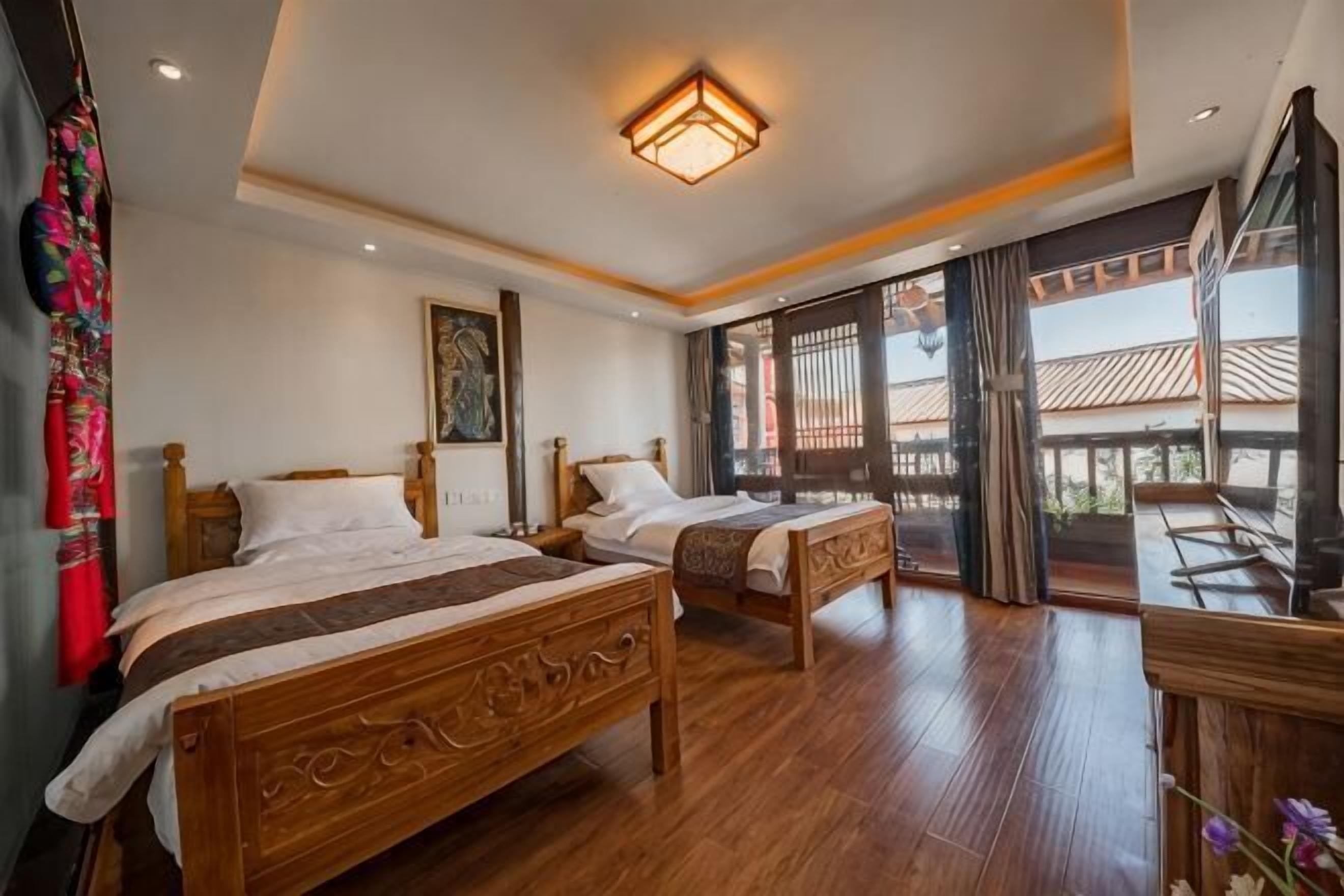 Ein Hotelzimmer mit zwei Holzbett, einem großen Fenster und einem Balkon.