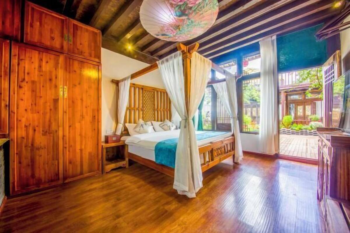 A room with a wooden bed, a nightstand, and a large window with a view of greenery.