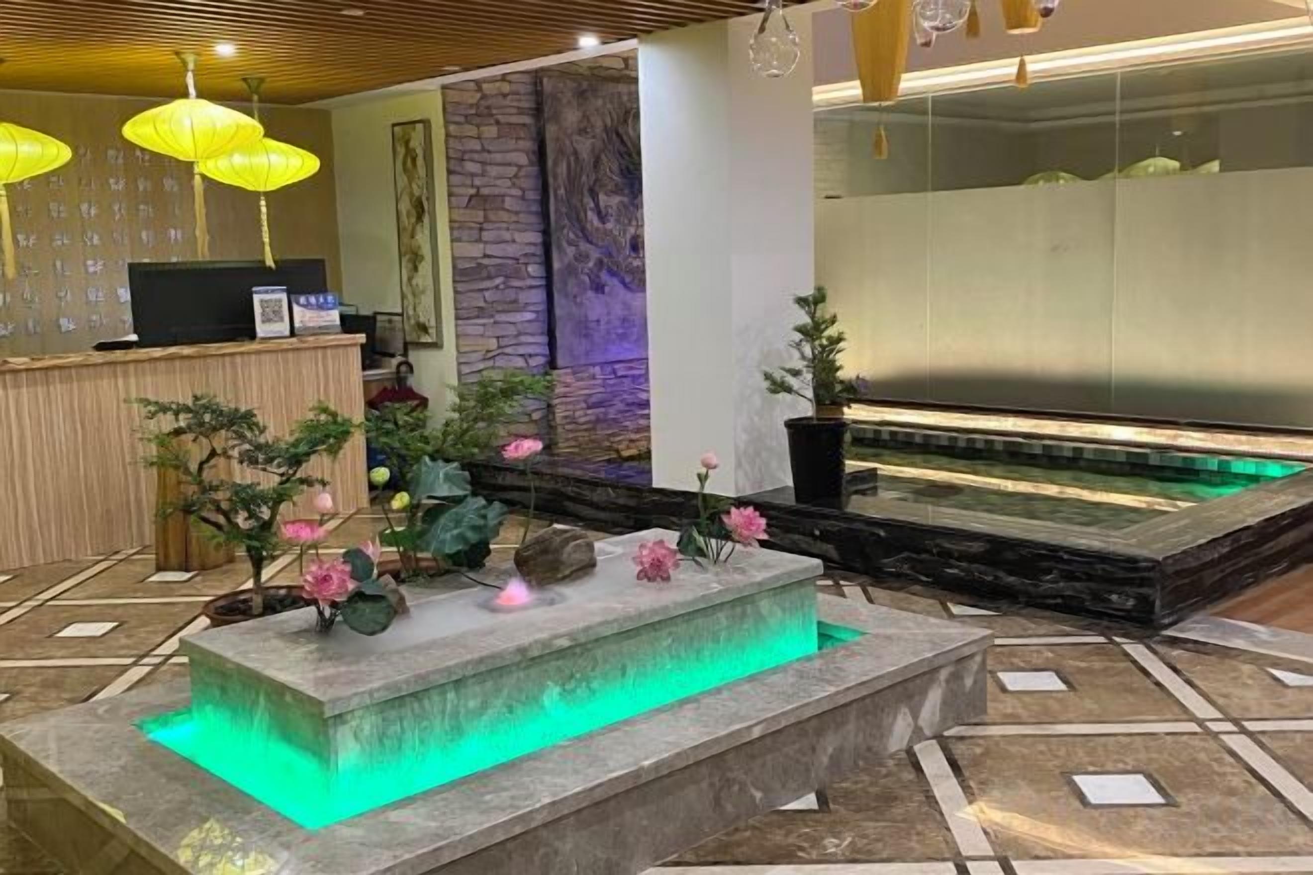 A reception area with a reception desk, a stone water feature with flowers, and a wall with a vertical garden.