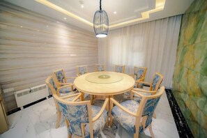 Un comedor con una mesa redonda y sillas, suelo de mármol y una lámpara moderna.