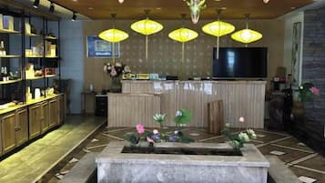 A hotel lobby with a reception desk, a television, and a decorative fountain.