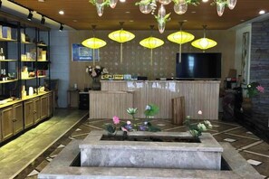 Un hall d’hôtel comprenant un comptoir d’accueil, un téléviseur et une fontaine décorative.
