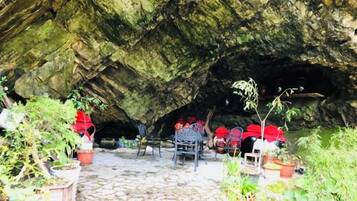 A cave interior with a paved floor, chairs, and potted plants.