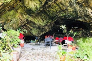 L'intérieur d'une grotte, avec un sol pavé, des chaises et des plantes en pot.