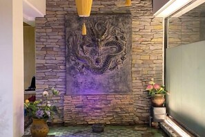 A stone wall with a dragon mural, a vase with flowers, and a potted plant. - Dexiju Hotel Shennongjia (Shennongjia)