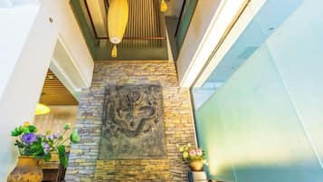 A stone wall with a dragon mural, a wooden ceiling, and a glass railing.