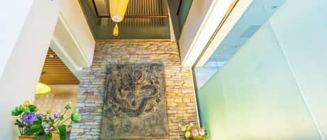 A stone wall with a dragon mural, a wooden ceiling, and a glass railing.