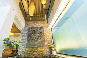 Pared de piedra con un mural de dragón, techo de madera y barandilla de cristal.