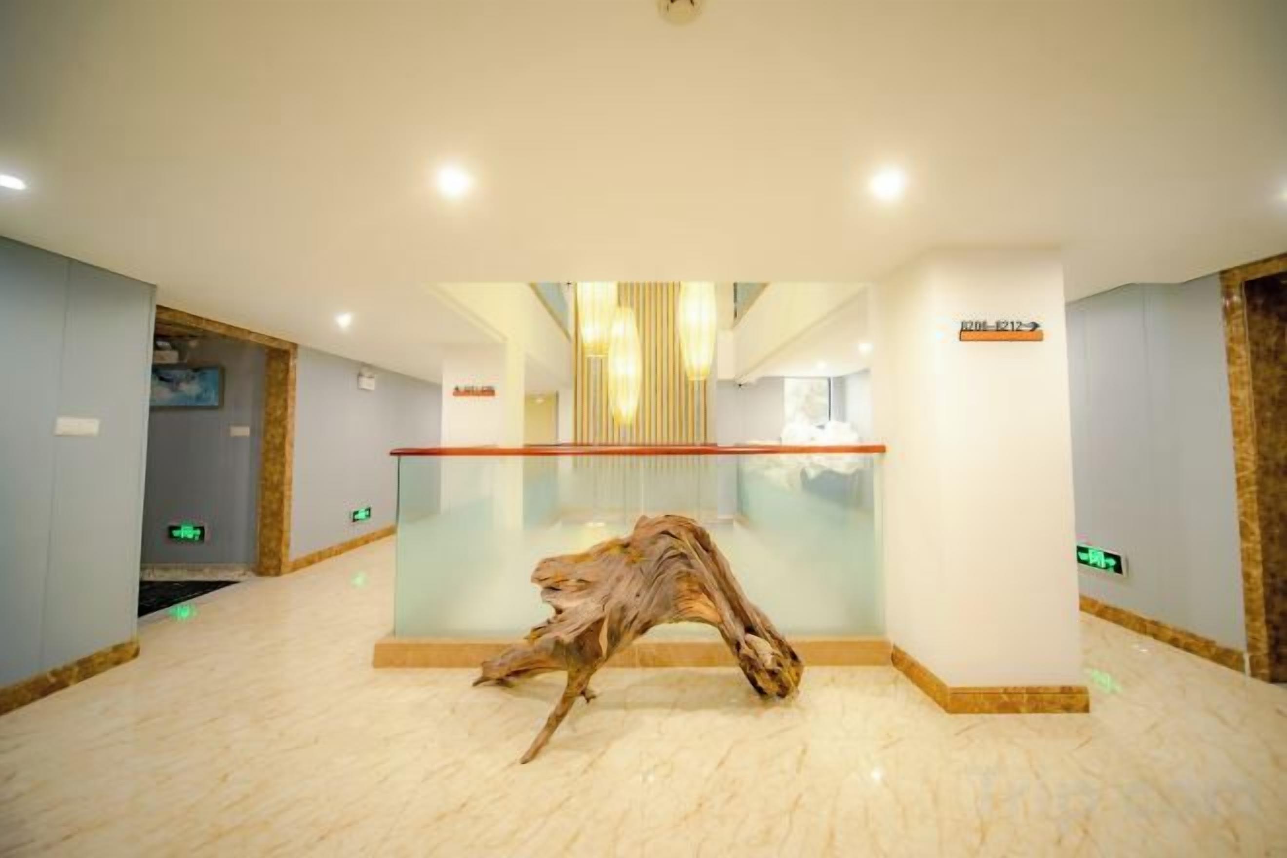 Un hall con un separador de vidrio, una escultura de madera y un letrero que indica la recepción.