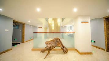 Un hall con un separador de vidrio, una escultura de madera y un letrero que indica la recepción.
