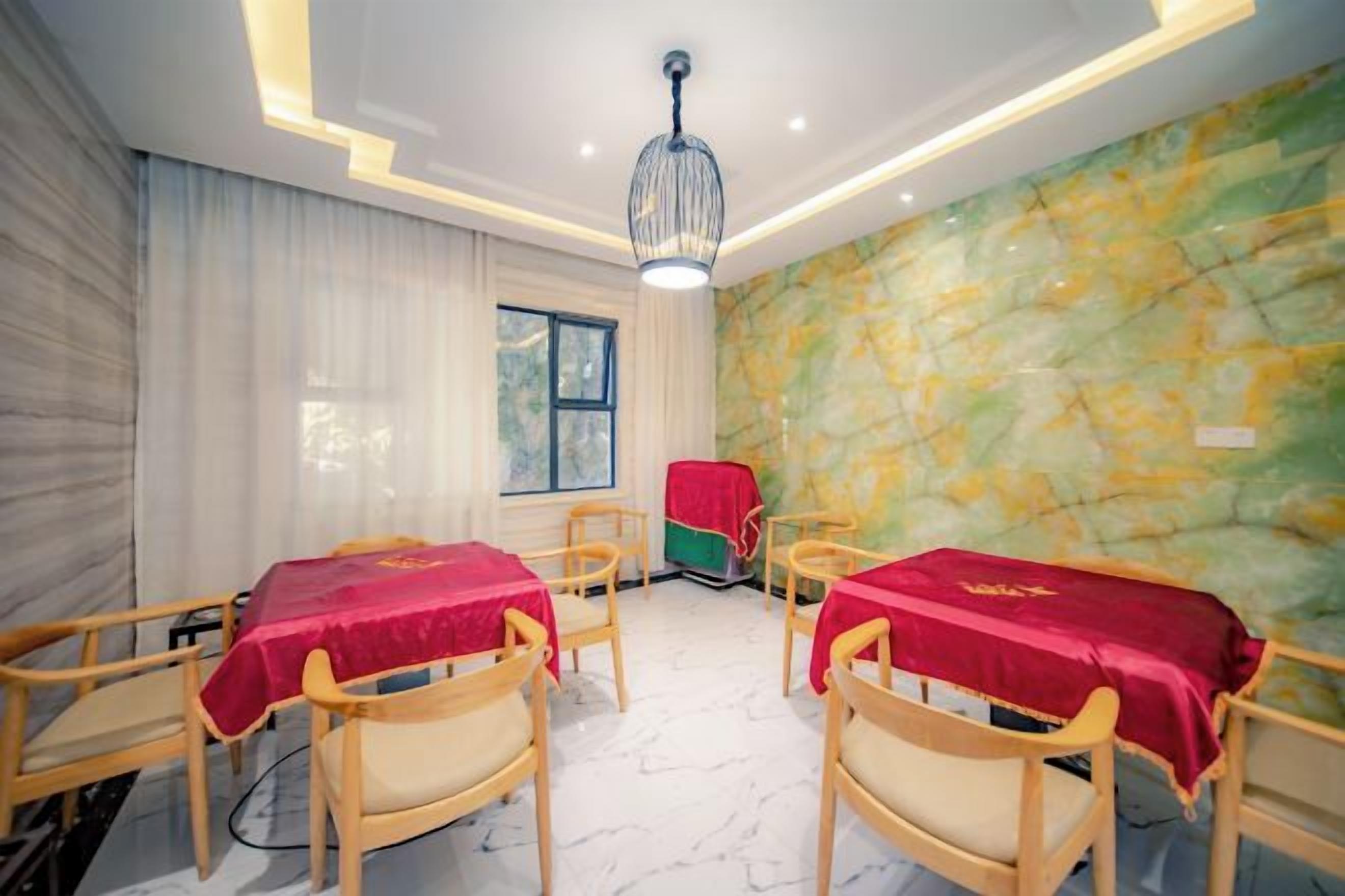 A room with a marble floor, wooden chairs, and tables with red tablecloths.