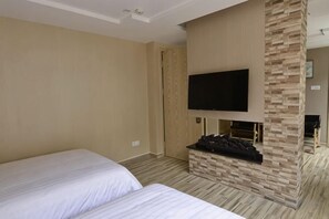 Une chambre d’hôtel avec deux lits, un téléviseur à écran plat fixé au mur et une cheminée.