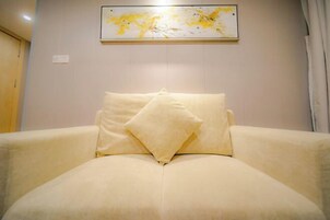 A bed with two pillows in a room with a plain wall and a light switch.