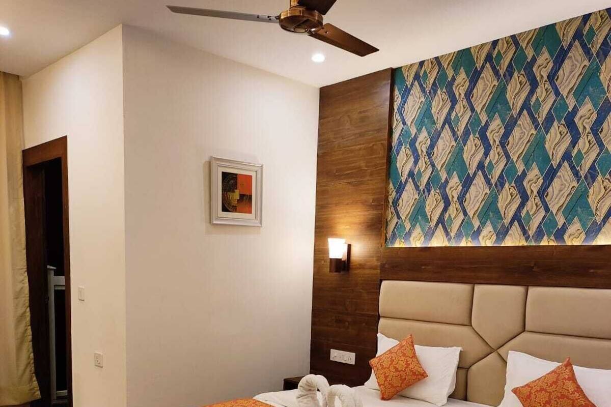 Camera d'albergo con un letto, una ventola a soffitto, una lampada a parete, una porta e una parete decorata.
