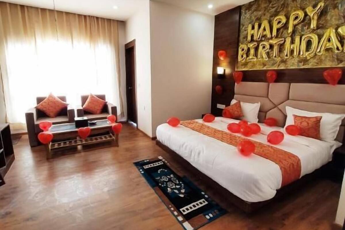 Una camera d'albergo moderna con un letto grande, un divano e una decorazione murale con la scritta 'Happy Birthday'.