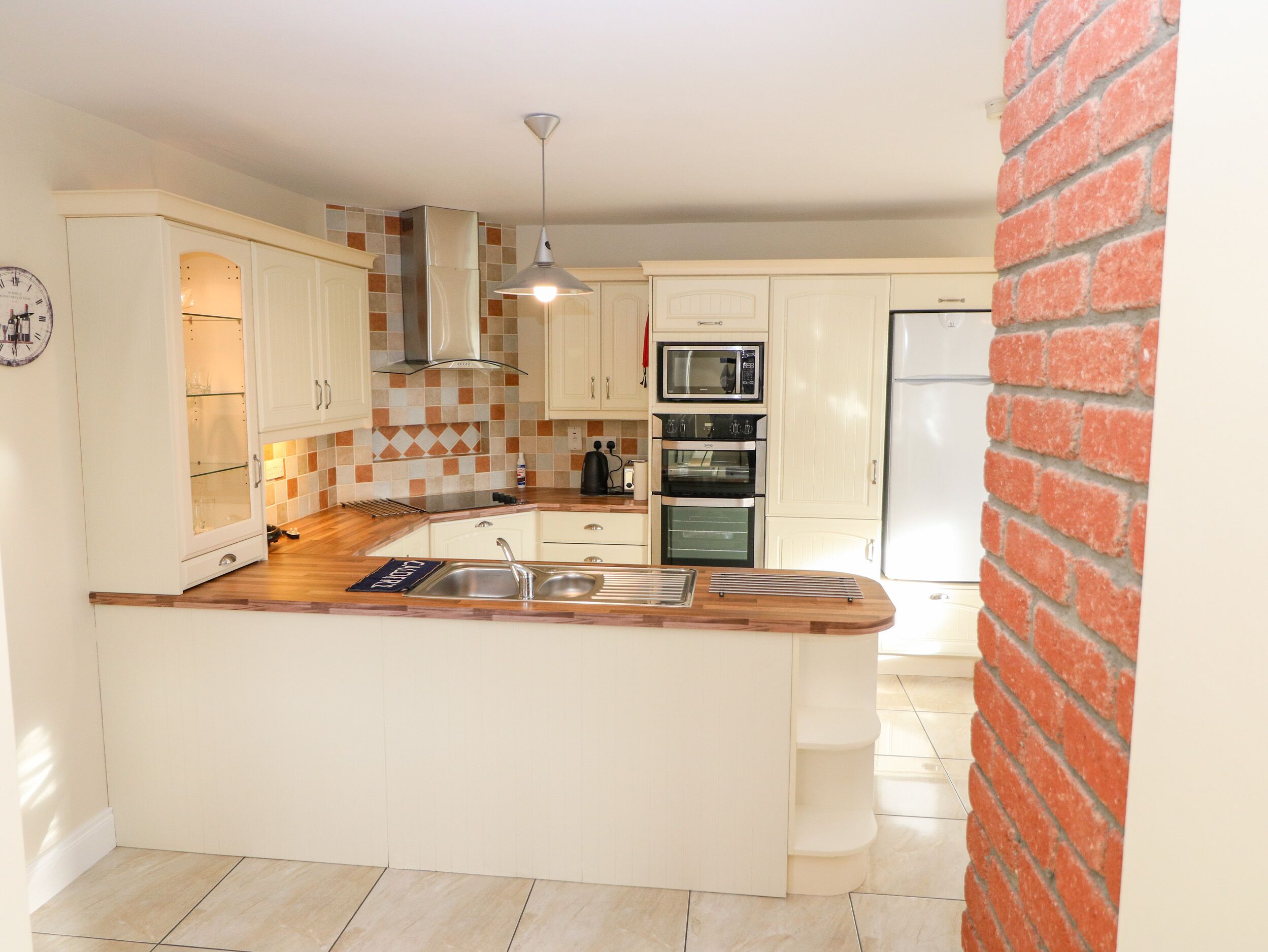 A compact kitchen with white cabinets, a built-in oven, a microwave, and a sink.