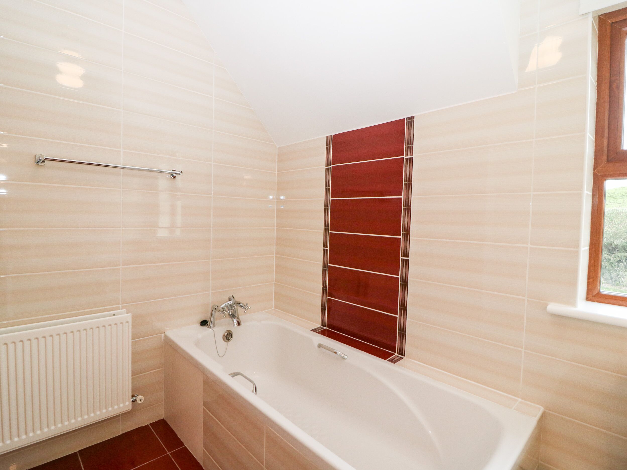 A bathroom with a bathtub, a towel rack, and a window.