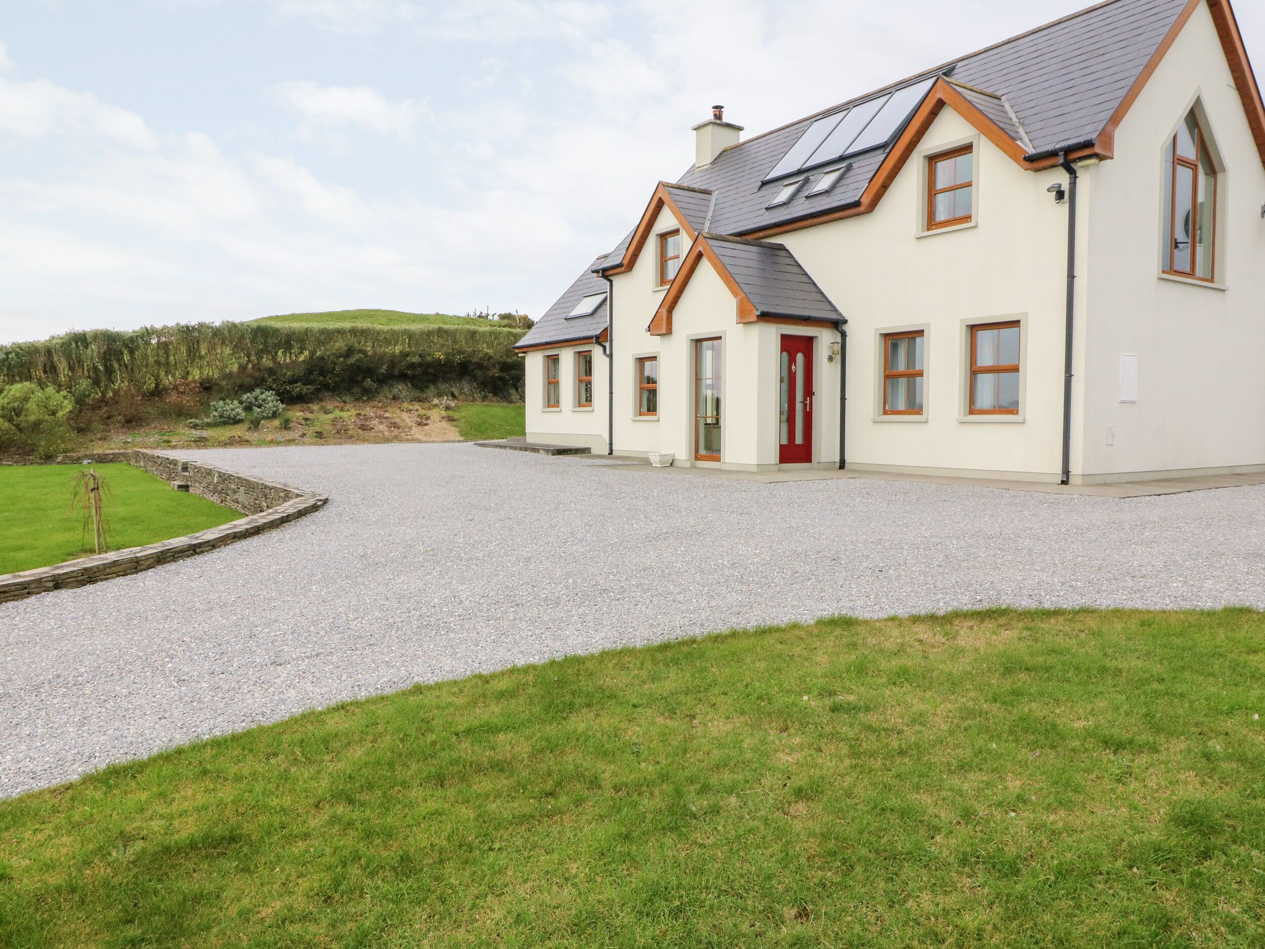 A two-story house with a gravel driveway and a red door.