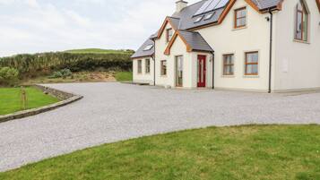 A two-story house with a gravel driveway and a red door.