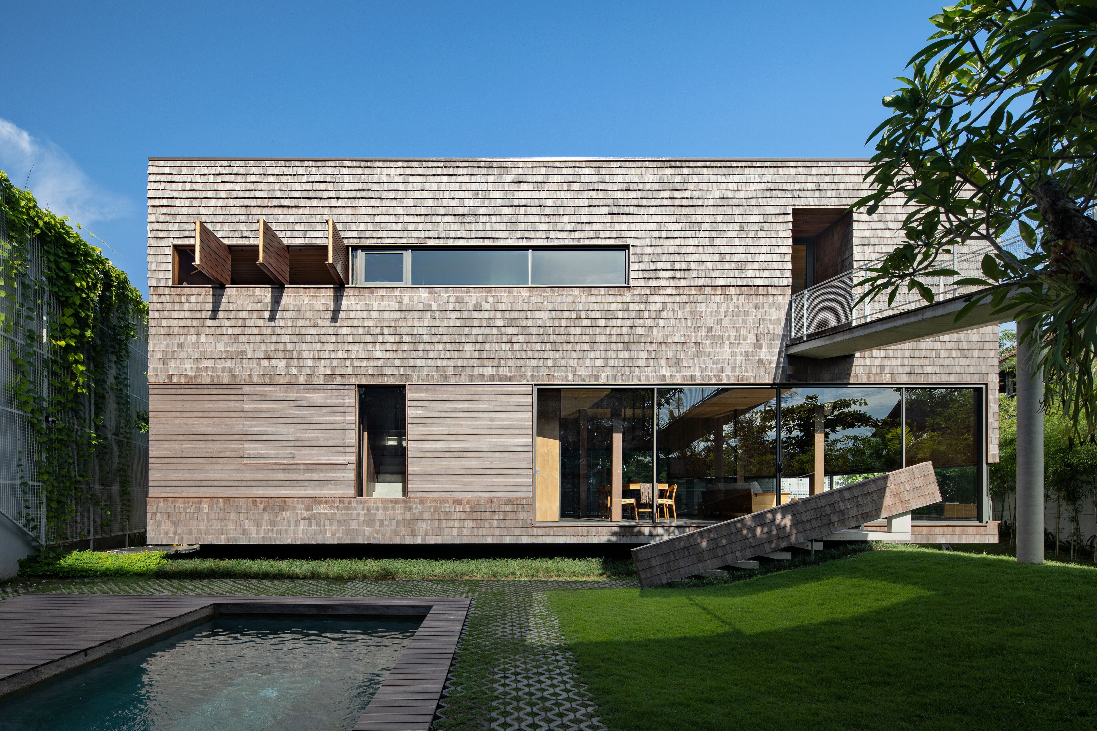 A modern house with a pool, a staircase, and a garden.